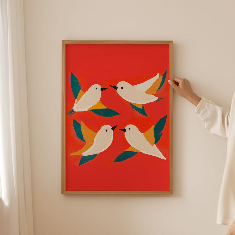 May include: A framed print with a red background and four white birds with yellow and green accents flying in different directions.