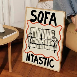 May include: A beige poster with a black and white illustration of a sofa. The poster has red wavy lines around the sofa and the text "SOFA NTASIC" in black.