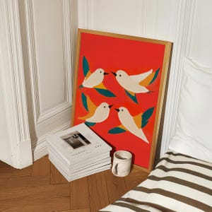 May include: A framed print with a red background and four white birds with orange and green accents flying in different directions.