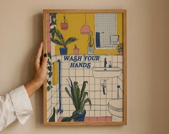 May include: A framed wall art print featuring a bathroom illustration with yellow walls, white tiled surfaces, and various potted plants. The text WASH YOUR HANDS is printed in blue in the center. The artwork includes a sink, toilet, and towel.