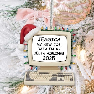 May include: A festive Christmas tree ornament in the shape of an old computer monitor and keyboard. The screen reads "JESSICA MY NEW JOB! DATA ENTRY DELTA AIRLINES 2025." A Santa hat sits on top. The ornament is adorned with multi-colored lights.