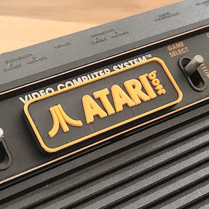 Atari 2600 / 2600+ カートリッジ スロット ダスト カバー - 4 スイッチ バージョン - ロゴとテキスト - オレンジ