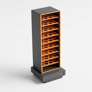 May include: A tall, rectangular storage tower with a dark gray exterior and a bright orange interior. The unit features eight horizontal shelves, each designed with a repeating hexagonal cutout pattern, and stands on a solid, matching gray base.