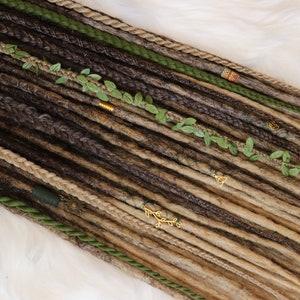 Könnte beinhalten: Ein Set aus braunen, blonden und grünen synthetischen Dreadlocks mit goldenen und grünen Perlen und Blattakzenten.
