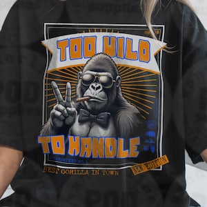 以下が含まれることがあります： サングラスと蝶ネクタイをしたゴリラのグラフィックが特徴の黒いTシャツ。ピースサインをして葉巻を持っています。「TOO WILD TO HANDLE」と「BEST GORILLA IN TOWN」というテキストが入っています。