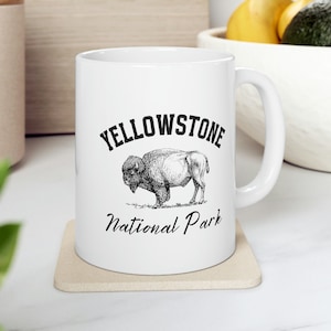 May include: White ceramic mug with a black and white illustration of a bison and the text "Yellowstone National Park".