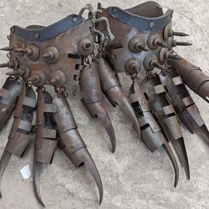 Pu&ograve; includere: Un paio di guanti di metallo usurato con lunghe estensioni curve a forma di artiglio. I guanti sono adornati con rivetti e punte e sono collegati da una corda. Il colore generale &egrave; marrone arrugginito.