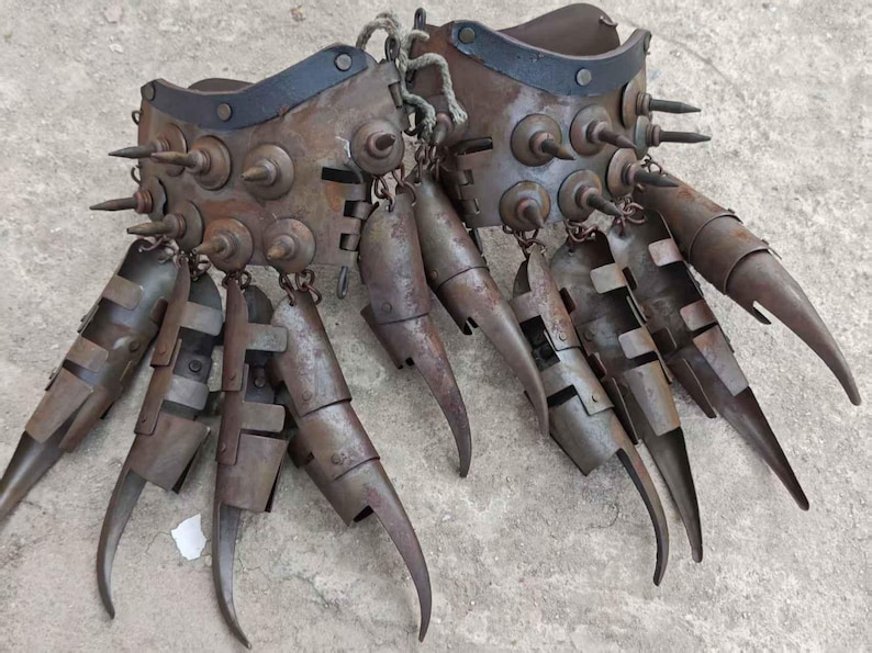 Pu&ograve; includere: Un paio di guanti di metallo usurato con lunghe estensioni curve a forma di artiglio. I guanti sono adornati con rivetti e punte e sono collegati da una corda. Il colore generale &egrave; marrone arrugginito.