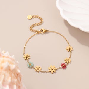Puede incluir: Pulsera dorada con abalorios de flores de margarita y peque&ntilde;as cuentas de colores. La pulsera tiene una cadena ajustable y un cierre seguro. Las flores est&aacute;n espaciadas uniformemente a lo largo de la cadena.