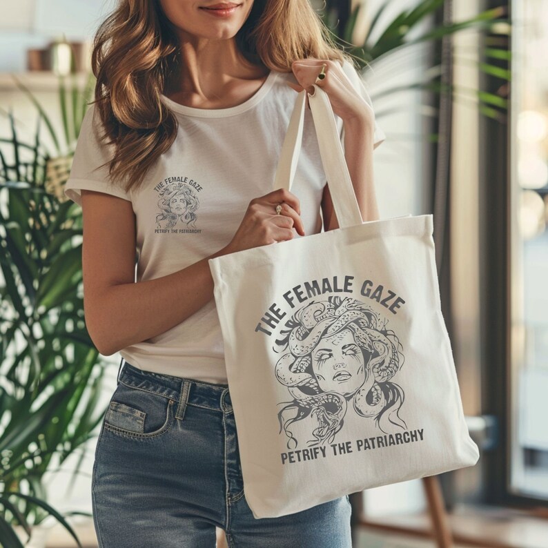 Puede incluir: Bolsa de tela blanca con una ilustraci&oacute;n en blanco y negro de una mujer con serpientes como cabello. El texto "The Female Gaze" y "Petrify the Patriarchy" est&aacute; impreso en la bolsa.