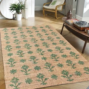 May include: A beige and green floral patterned jute rug. The rug has a woven texture and features a repeating pattern of green flowers on a beige background.