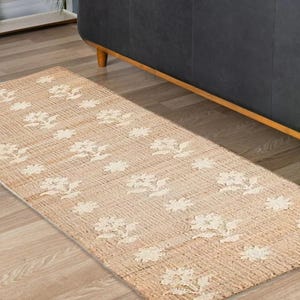 May include: A beige and white runner rug with a floral pattern. The rug is made of natural fibers and has a woven texture.
