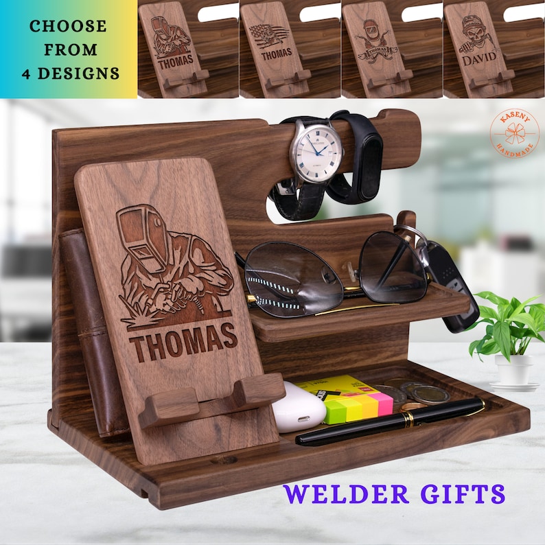 May include: A wooden desk organizer with multiple compartments. It features a phone stand with a welder design and the name "THOMAS". The organizer also has a watch holder, sunglasses shelf, and a tray. The text "CHOOSE FROM 4 DESIGNS" and "WELDER GIFTS" are visible.