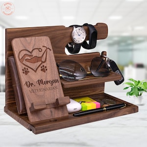 May include: Wooden desktop organizer with a phone stand, watch holder, glasses holder, and a small tray. It is personalized with the text "Dr. Morgan Veterinarian" and a heart with a paw print design.