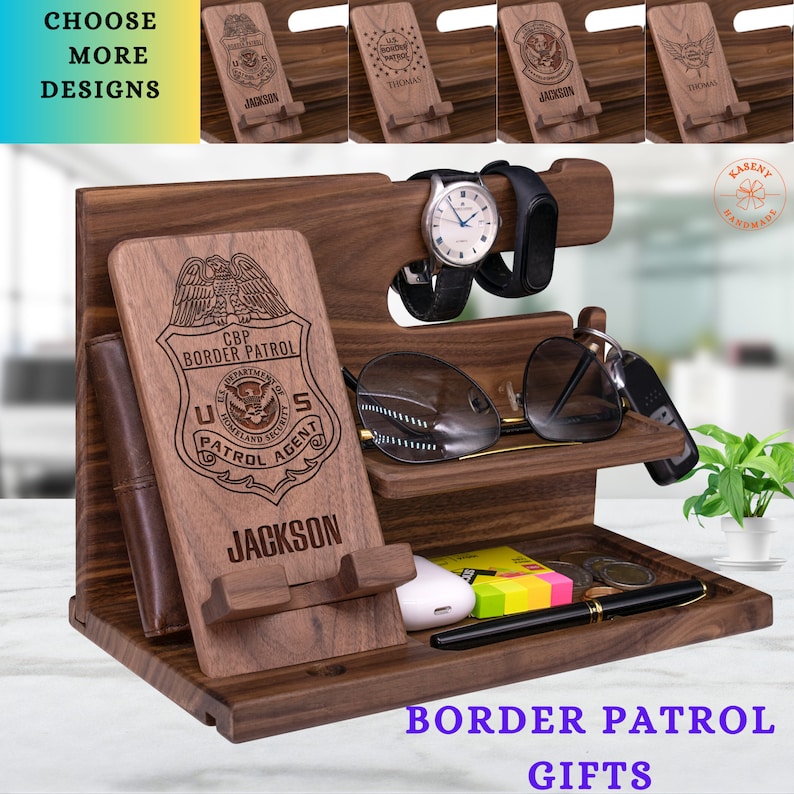 May include: A wooden phone stand with a leather wallet, watch holder, glasses holder, and key holder. The stand is engraved with the words "CBP Border Patrol" and "U.S. Patrol Agent".