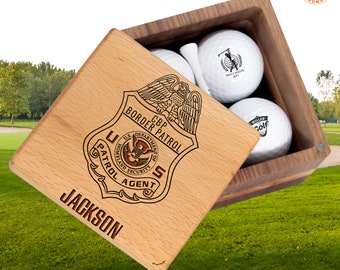 May include: A wooden box with a hinged lid, engraved with a CBP Border Patrol badge and the name "JACKSON". The box contains three golf balls.