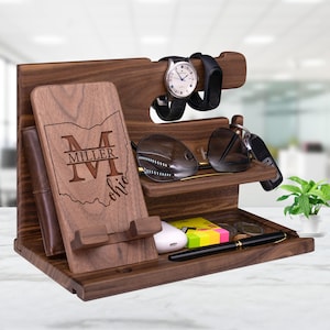 May include: A wooden organizer with multiple compartments for holding items like a phone, watch, keys, and glasses. The organizer is personalized with the name "Miller" and the state of Ohio.