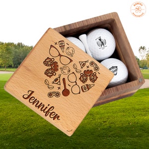 May include: A wooden box with a personalized engraved lid featuring an eye exam theme and the name Jennifer. The box contains three white golf balls with the text "Phil J. Miller 2023" and "Miller Golf" on them.