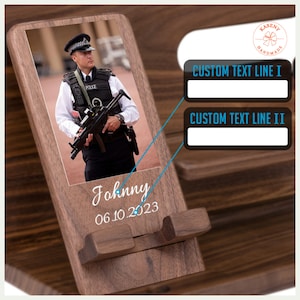 May include: Wooden phone stand with a photo of a police officer, the name "Johnny", and the date "06.10.2023" printed in white. Features two lines for custom text. The stand is made of dark wood.