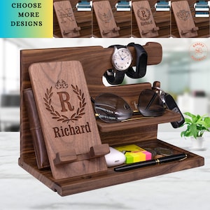 May include: A wooden organizer with multiple compartments for holding a phone, watch, keys, and other items. The organizer is personalized with the name "Richard" and a monogrammed "R" with a laurel wreath design. The organizer is made of walnut wood and has a natural finish.