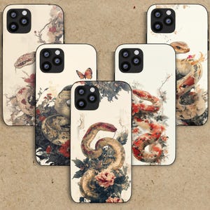Peut inclure: Ensemble de six coques de téléphone avec un fond blanc orné d'un motif floral et d'un serpent. Les serpents sont de différentes couleurs et motifs, notamment rouge, marron et noir. Les coques sont conçues pour les iPhones.