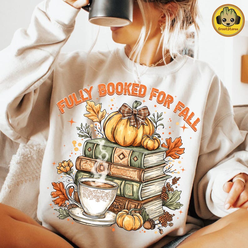 May include: A cream-coloured sweatshirt with the text "FULLY BOOKED FOR FALL" in orange. The graphic shows a stack of books, a pumpkin with a plaid bow, a cup of coffee, and autumn leaves.