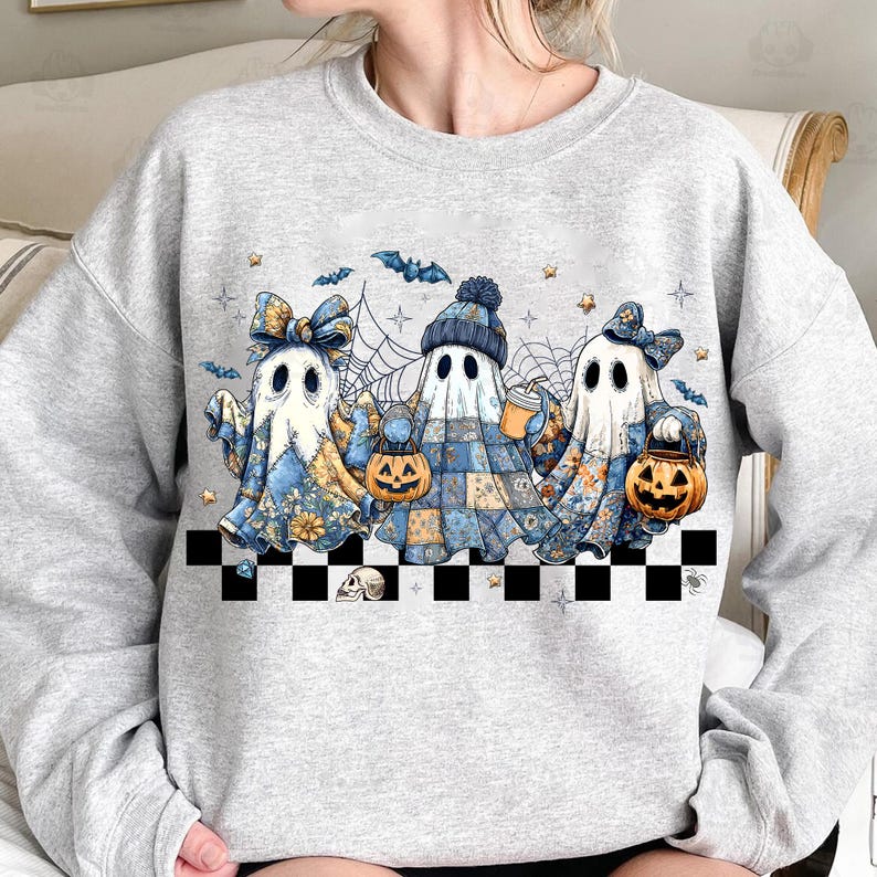 K&ouml;nnte beinhalten: Hellgraues Sweatshirt mit einer Grafik von drei Cartoon-Geistern in blau-gelben Mustern, die K&uuml;rbislaternen und Getr&auml;nke halten. Das Design umfasst Flederm&auml;use, Spinnweben und Sterne mit einem schwarz-wei&szlig;en Schachbrettmuster.