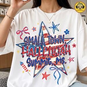 Puede incluir: Una camiseta blanca con un gran gráfico de estrella central con un patrón de bandera estadounidense en rojo, blanco y azul. El texto SMALL TOWN, HALLELUJAH, SUMMIT, MS. aparece en letras azules y rojas, rodeado de estrellas, lazos y un cohete.