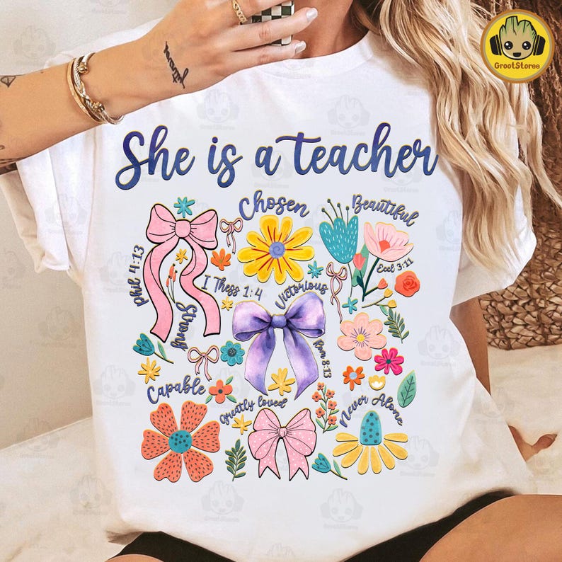 Puede incluir: Camiseta blanca con el texto "She is a teacher" y un dise&ntilde;o floral con lazos y vers&iacute;culos b&iacute;blicos. Los vers&iacute;culos incluyen "Phil 4:13", "I Thess 1:4", "Rom 8:13", "Ecel 3:11".
