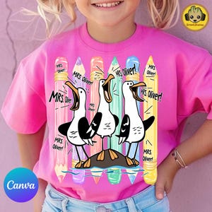 May include: A bright pink t-shirt featuring a graphic print of three cartoon seagulls standing on a rock. Behind the birds are six vertical colored pencils in pink, purple, orange, teal, blue, and yellow. The text "MRS. Oliver!" appears repeatedly.