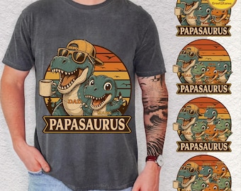 May include: Dark gray t-shirt featuring a graphic of two cartoon dinosaurs, one wearing sunglasses and a hat, holding a mug, and the other waving. The text "PAPASAURUS" is below the dinosaurs.