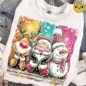 Può includere: Felpa girocollo bianca con una grafica colorata di Babbo Natale, una renna e un pupazzo di neve. L'illustrazione ha un effetto acquerello con fiocchi di neve e uno sfondo vibrante arancione, blu e rosa.