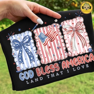 May include: Black towel with patriotic designs. Features three framed images with bows, flags, and stars in red, white, and blue. Text reads "GOD BLESS AMERICA LAND THAT I LOVE."