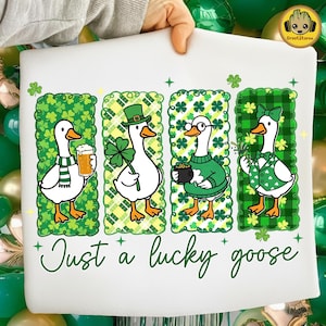 May include: White t-shirt featuring four cartoon geese in green St. Patrick's Day attire. Each goose is in a different pose, holding a beer, a shamrock, a pot of gold, and a sprig of shamrocks. The text "Just a lucky goose" is written in green script.