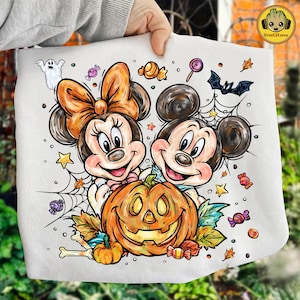 May include: White tote bag featuring Mickey and Minnie Mouse with a carved pumpkin, spiderwebs, candy, and a bat. The design has a Halloween theme with fall colors and cartoon illustrations.