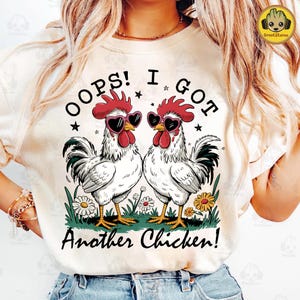Könnte beinhalten: Weißes T-Shirt mit einem Motiv von zwei Hühnern mit Sonnenbrillen und dem Text "Oops! I got another chicken!"
