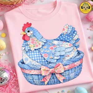 May include: A pale pink t-shirt with a colourful appliqué design of a hen in a basket. The hen is blue with floral and gingham patterns, a red comb, and a yellow beak. The basket is blue with a floral bow. The design is centered.