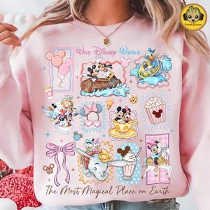 May include: Pink sweatshirt featuring various Disney characters and icons, including Mickey and Minnie Mouse, Donald Duck, and Dumbo. The design includes the text "Walt Disney World" and "The Most Magical Place on Earth."