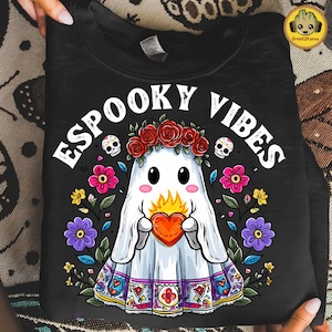 May include: Black sweatshirt featuring a ghost holding a heart, surrounded by flowers and the words "ESPOOKY VIBES". The ghost wears a floral crown and has a colourful patterned border.