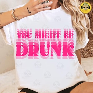 Puede incluir: Camiseta blanca con la frase "YOU MIGHT BE DRUNK" en letras rosas superpuestas. Una prenda casual para el uso diario.