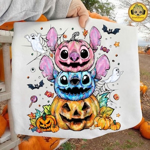 Op de afbeelding: Witte Halloween-draagtas met een ontwerp van gestapelde uitgesneden pompoenen in roze, blauw en oranje, die lijken op Stitch-personages. Inclusief geesten, vleermuizen en snoep. Een seizoensgebonden, spookachtig ontwerp.