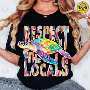 May include: Black t-shirt with a colorful sea turtle and the text "Respect the Locals" in a rainbow paint splatter design.