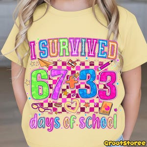May include: A light yellow t-shirt with the text "I SURVIVED 67+33 days of school" in colorful bubble letters. The shirt features school-themed graphics like a paper airplane, pencil, and stars.