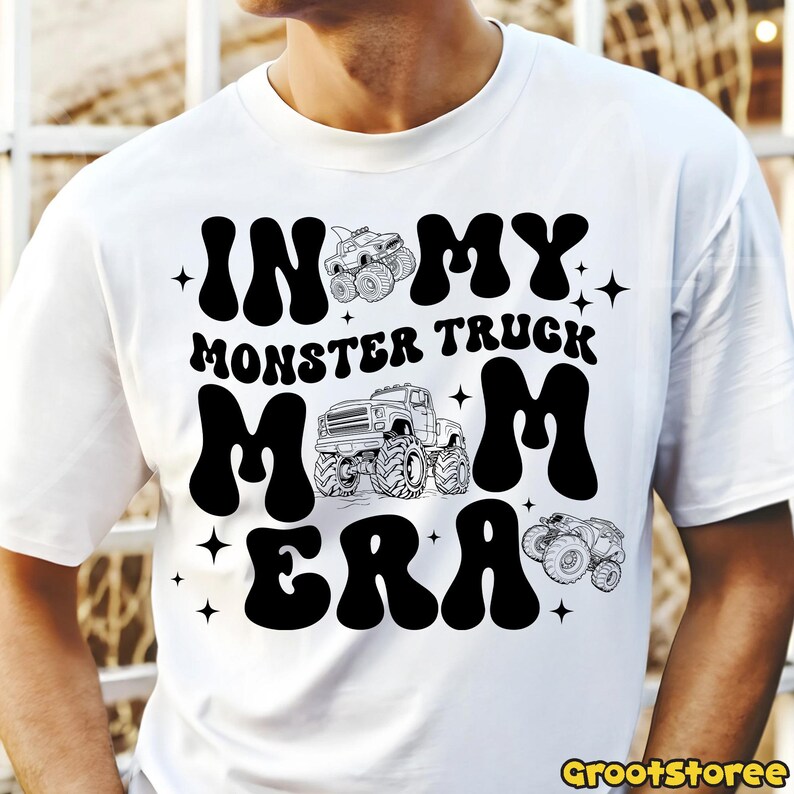K&ouml;nnte beinhalten: Wei&szlig;es T-Shirt mit schwarzem Grafikdesign. Das Design zeigt den Text "IN MY MONSTER TRUCK MOM ERA" in einer fetten, retro Schriftart, zusammen mit Illustrationen von Monstertrucks und Sternen. Das Shirt ist ein l&auml;ssiger Alltagsartikel.