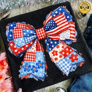 May include: A patriotic bow featuring the American flag, red and white stripes, and blue star patterns. The bow is made of patchwork fabric with floral and gingham patterns, perfect for Independence Day celebrations.