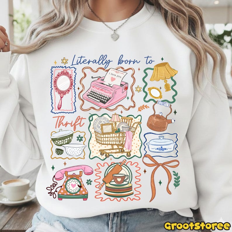 May include: White sweatshirt with a colorful graphic design featuring vintage items like a pink typewriter, mirror, and shopping cart. The text "Literally born to Thrift" is displayed above the images. The design includes a telephone, dishes, and a teapot.