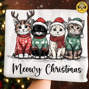 May include: A white rectangular pillow featuring four cats dressed for Christmas. The cats wear Santa hats and sweaters with reindeer and snowflake designs. The text "Meowy Christmas" is written in a script font at the bottom.
