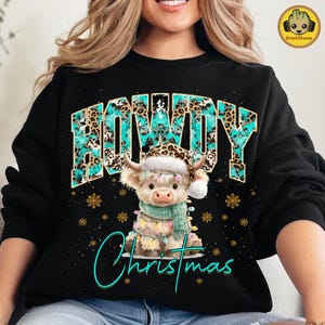 May include: Black sweatshirt with the word "HOWDY" in a turquoise and leopard print design. A cartoon cow wearing a Santa hat and scarf is in the center, with the word "Christmas" below. Gold snowflakes and lights are also featured.