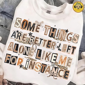 Puede incluir: Sudadera blanca con el texto "SOME THINGS ARE BETTER LEFT ALONE LIKE ME FOR INSTANCE" en un estilo collage. El texto utiliza varias fuentes y patrones, incluyendo estampado de leopardo, con estrellas y lazos.