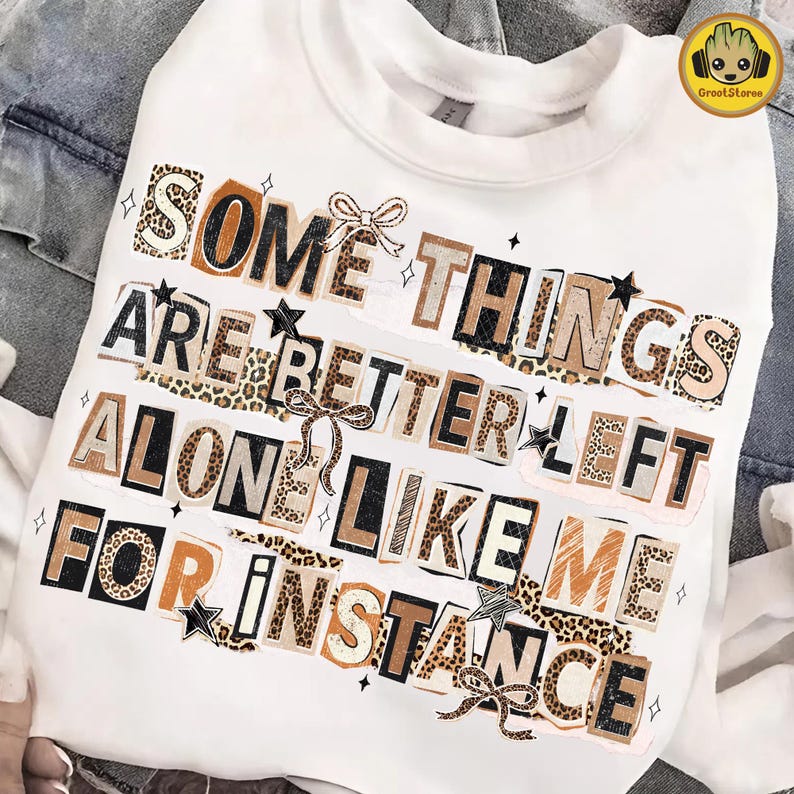 Puede incluir: Sudadera blanca con el texto "SOME THINGS ARE BETTER LEFT ALONE LIKE ME FOR INSTANCE" en un estilo collage. El texto utiliza varias fuentes y patrones, incluyendo estampado de leopardo, con estrellas y lazos.